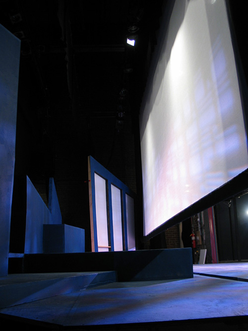 The set as seen from the right wing during tech week. The scrim's weighted bottom flies into a 5" gap in the stage floor. A cyclorama is hung behind the set. (Click images for larger versions in new window.)