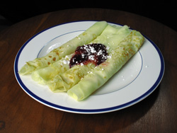 Gluten-free crêpes filled with a little sour cream and garnished with raspberry preserves and unsifted (clumpy) confectioner's sugar.